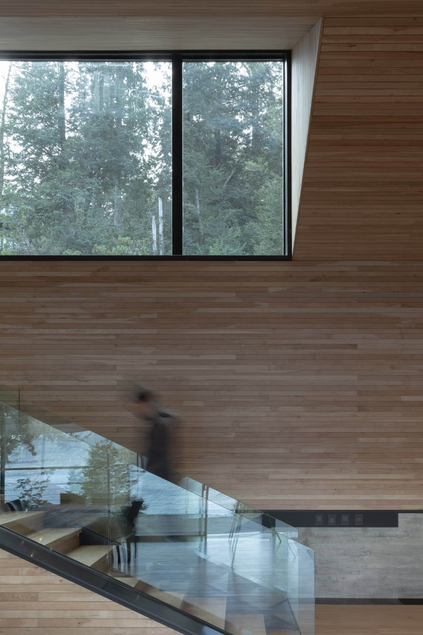 Motion blur of person descending the staircase with large picture window.
