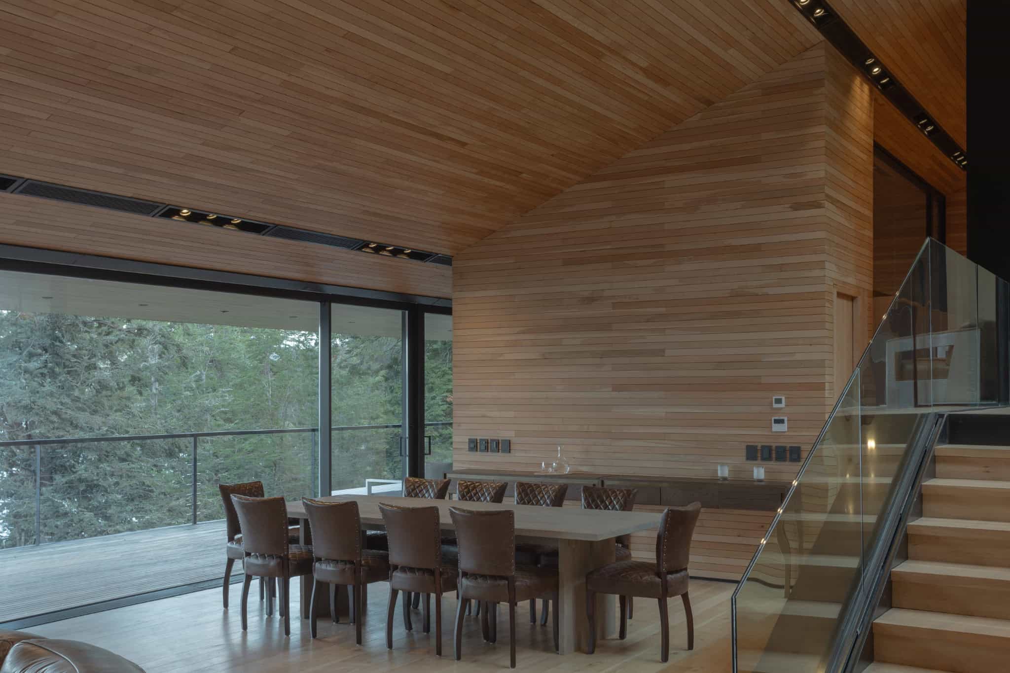 Warm wooden interior dining room of VLA House by A4estudio with forest view.