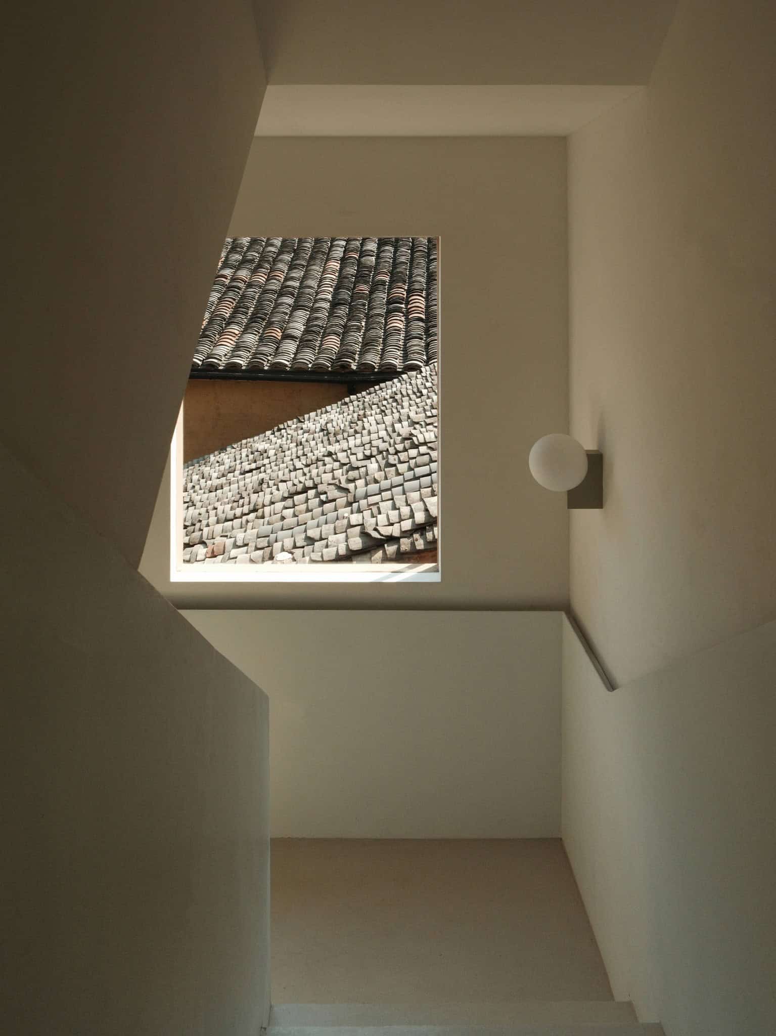 Modern Interior Contrasts with Ancient Eaves Framed view of tiled rooftops through minimalist modern interior window