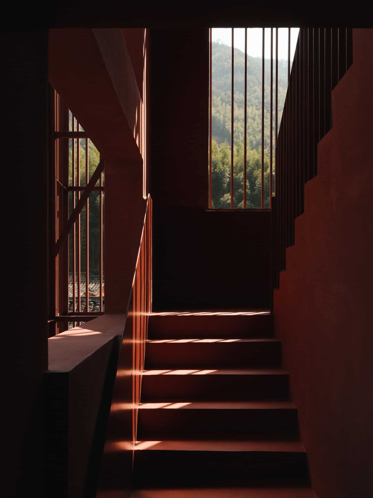 Third Floor Staircase as Semi-Outdoor Red staircase on third floor leading to rooftop, bathed in natural light