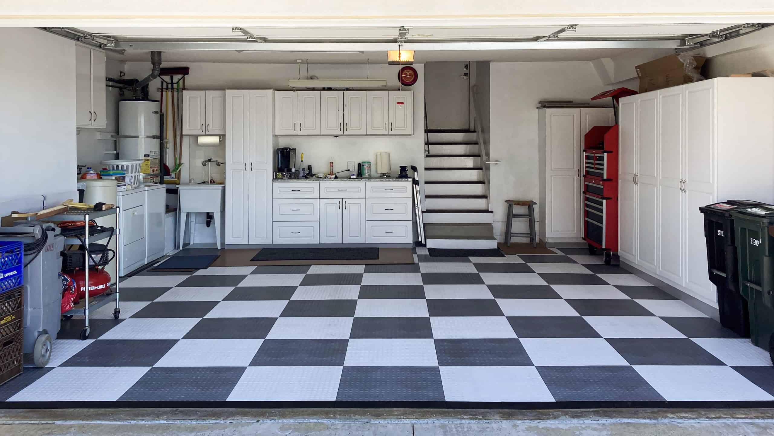 Why Garage Flooring Matters: Protect Your Investment Organized residential garage with checkered black and white flooring, white storage cabinets, and integrated laundry area.