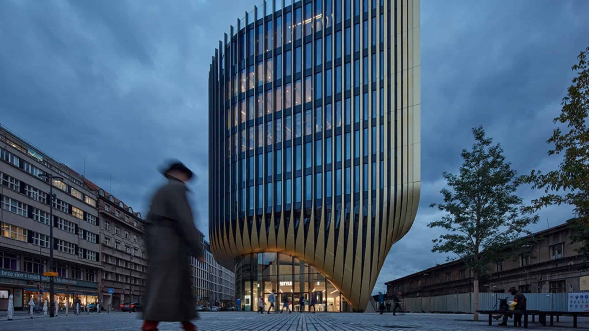Futuristic modern office building with curved gold exterior panels and glass windows, urban cityscape at dusk, innovative architecture design emphasizing contemporary commercial architecture.