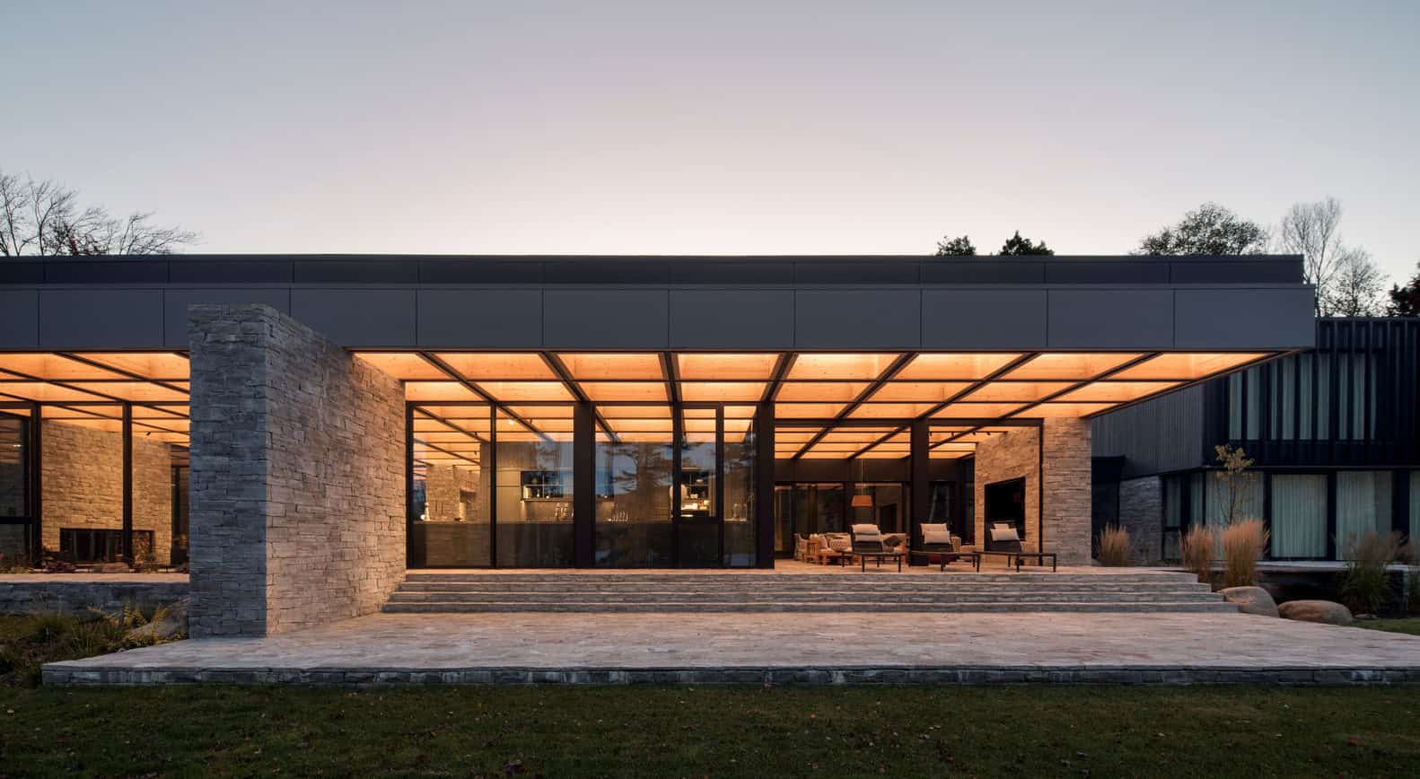 Elegant modern house with sleek architectural design, stone accents, expansive glass windows, and warm lighting, showcasing contemporary residential architecture and innovative outdoor living spaces.