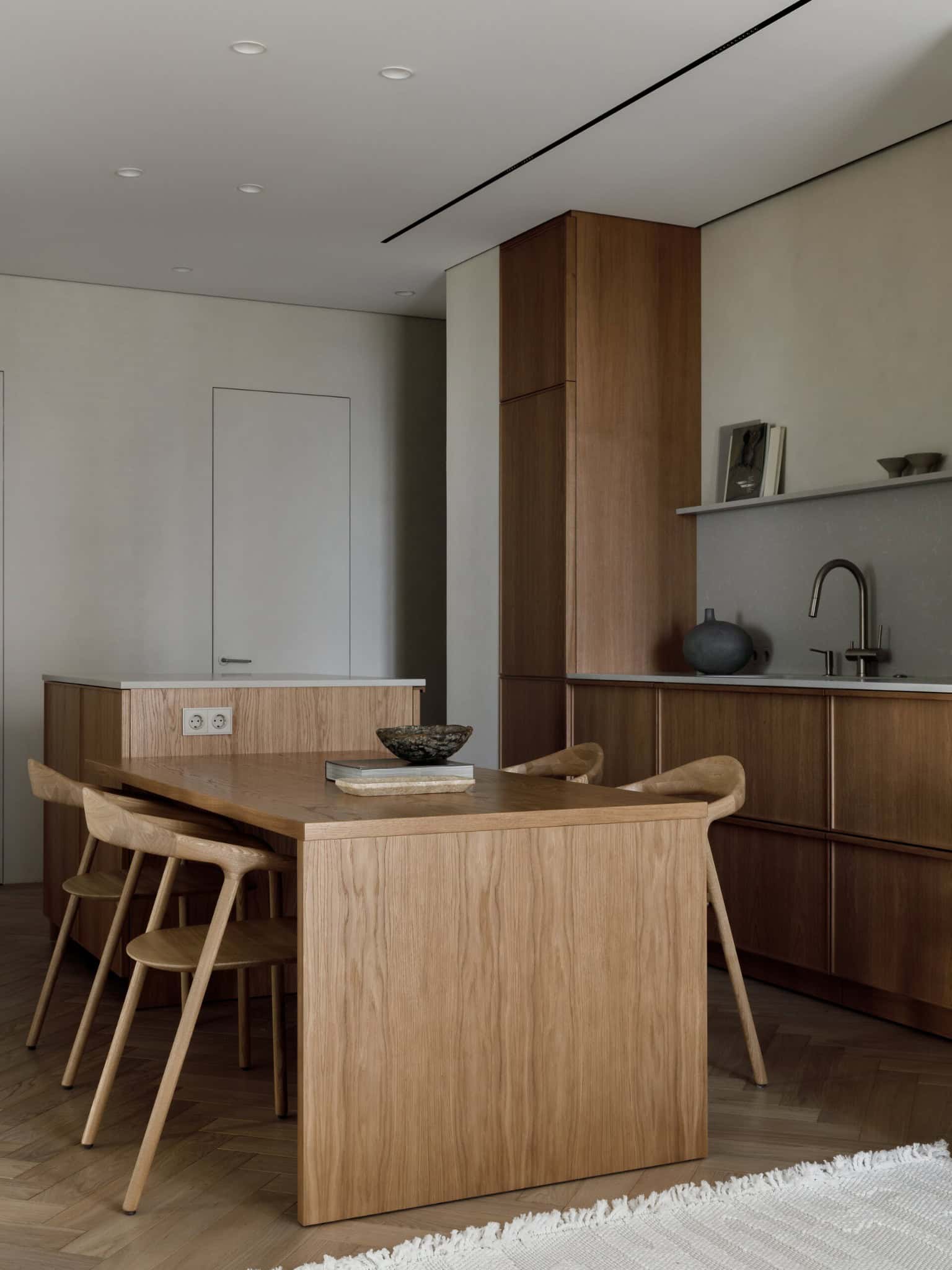 Sleek modern kitchen with minimalist wooden cabinetry and dining table, featuring natural materials and clean design for contemporary architecture and interior design enthusiasts.