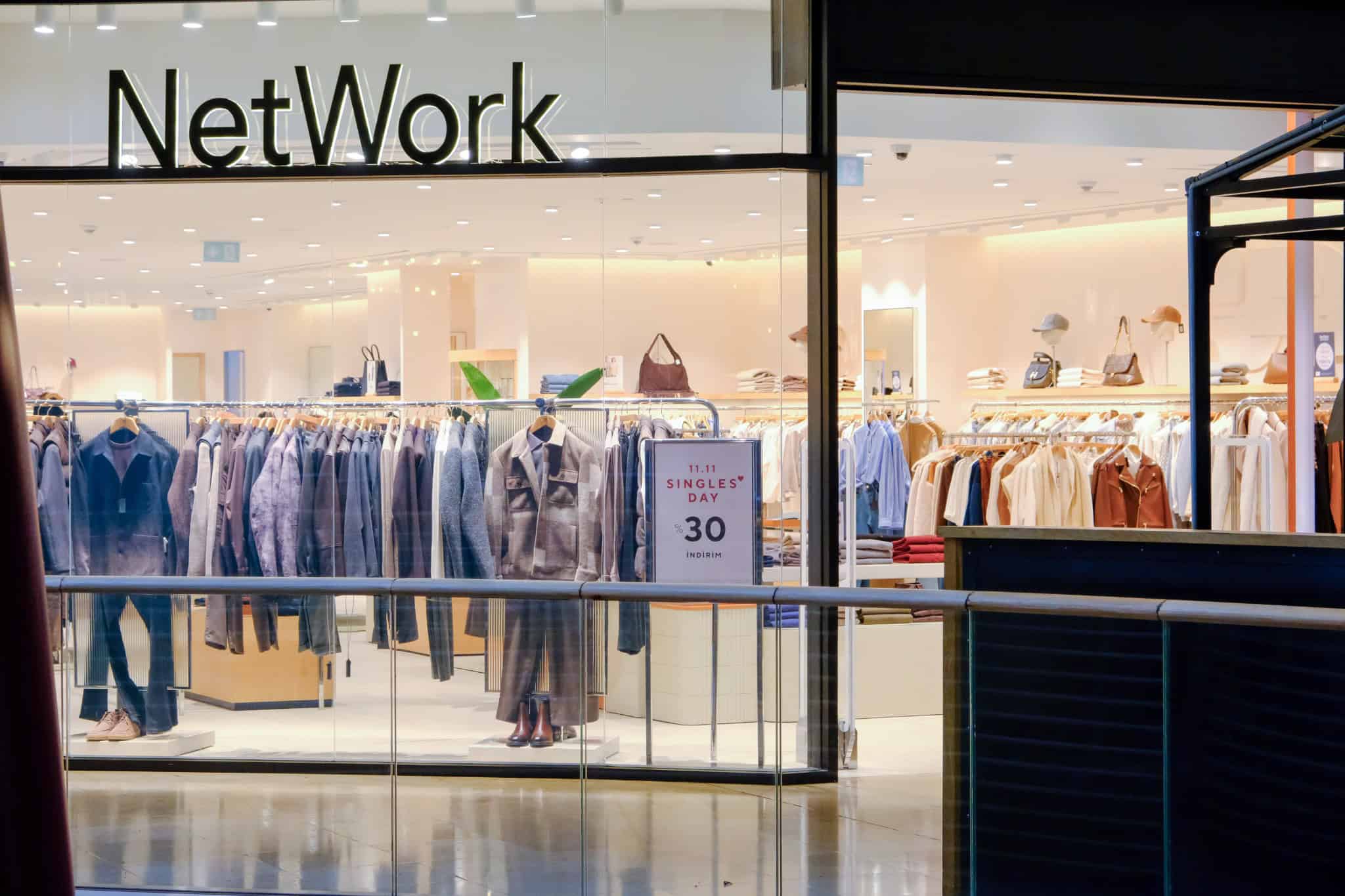 Contemporary retail store with modern interior design, clothing displays, and promotional signage, showcasing stylish fashion merchandise in an elegant shopping environment.