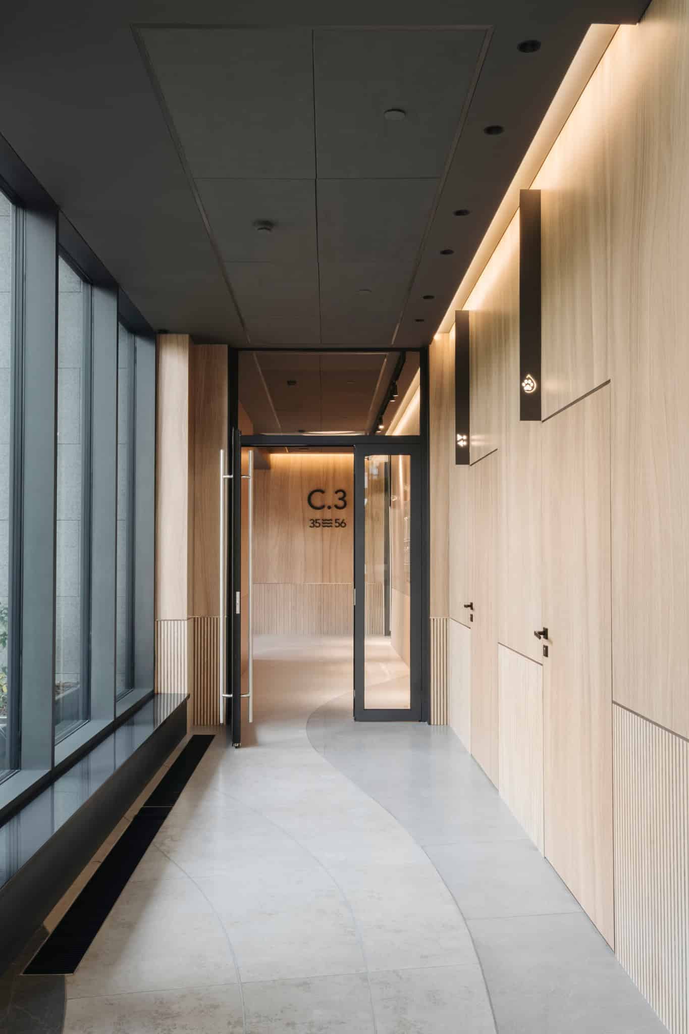 RIVER Corridor C3 Entrance by VSA.studio Contemporary minimalist interior design featuring sleek wood paneling, modern lighting, and large glass windows for natural light, ideal for architectural art and modern interior projects.