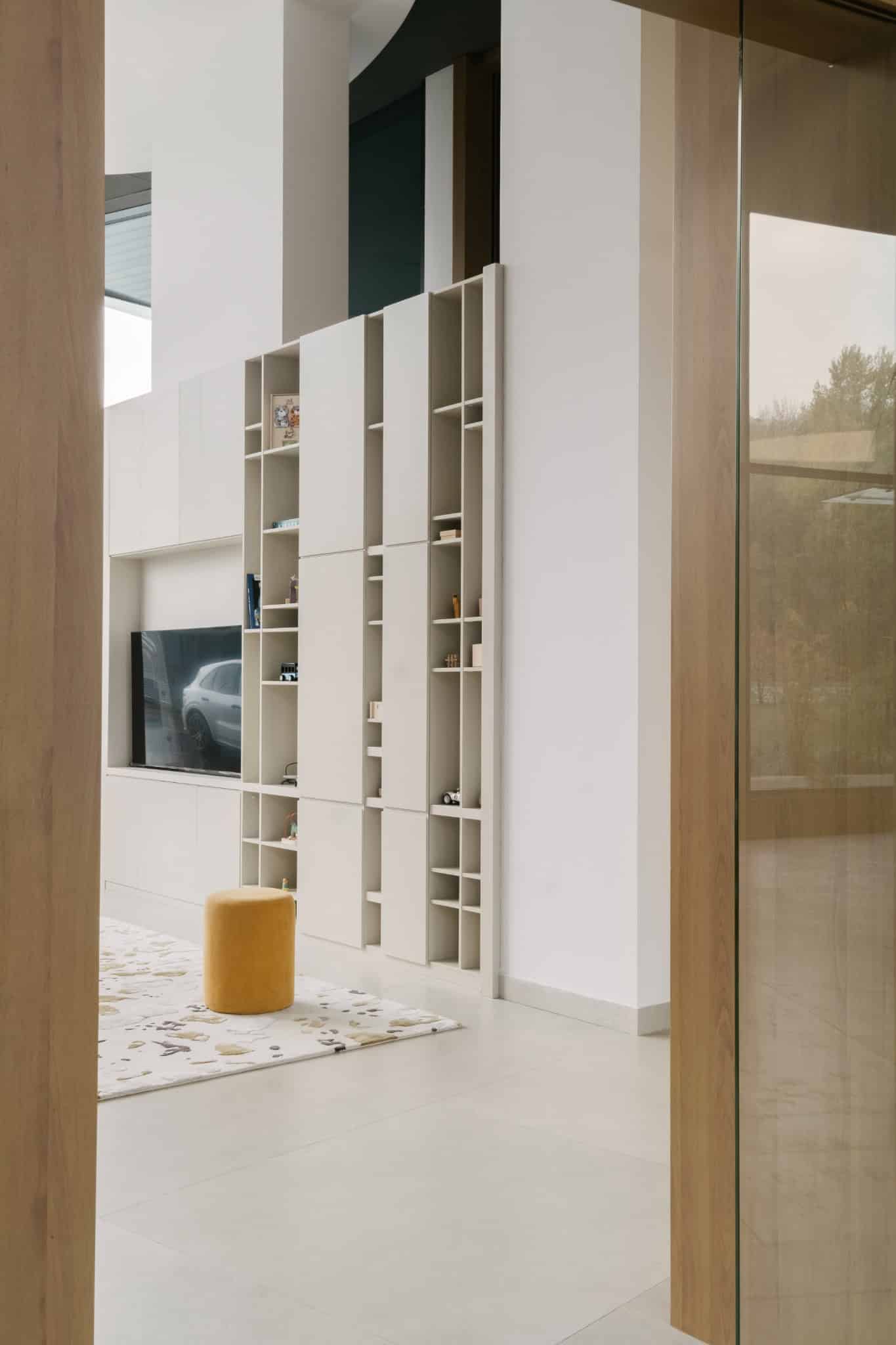 RIVER Kids Playroom Overview by VSA.studio Contemporary interior design featuring custom white modular shelving unit with open cubbies and an integrated TV, minimalist decor, clean lines, and natural light for modern home aesthetics.