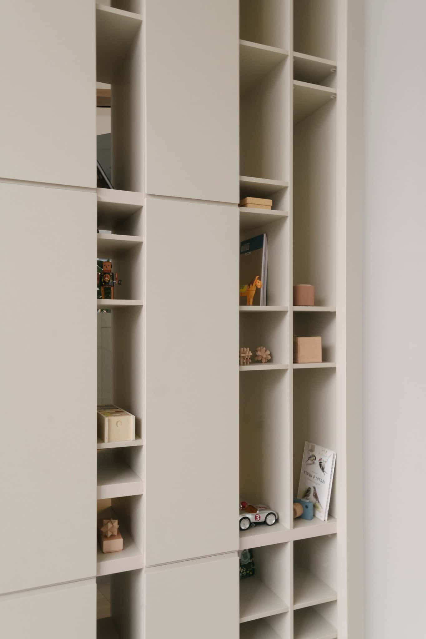 RIVER Kids Shelving Detail by VSA.studio Sleek modern built-in white shelving unit with storage compartments and decorative items, ideal for contemporary interior design and functional home organization.