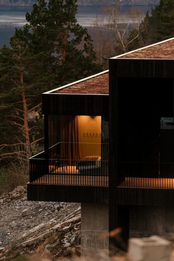 18-07 Holiday Home Bedroom Balcony Night by OFFICE INAINN 18-07 Holiday Home by OFFICE INAINN, illuminated bedroom opening to balcony overlooking fjord at night