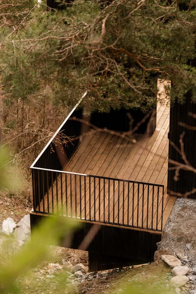 18-07 Holiday Home Lower Deck View by OFFICE INAINN 18-07 Holiday Home by OFFICE INAINN, lower timber deck among pines above Norwegian fjord