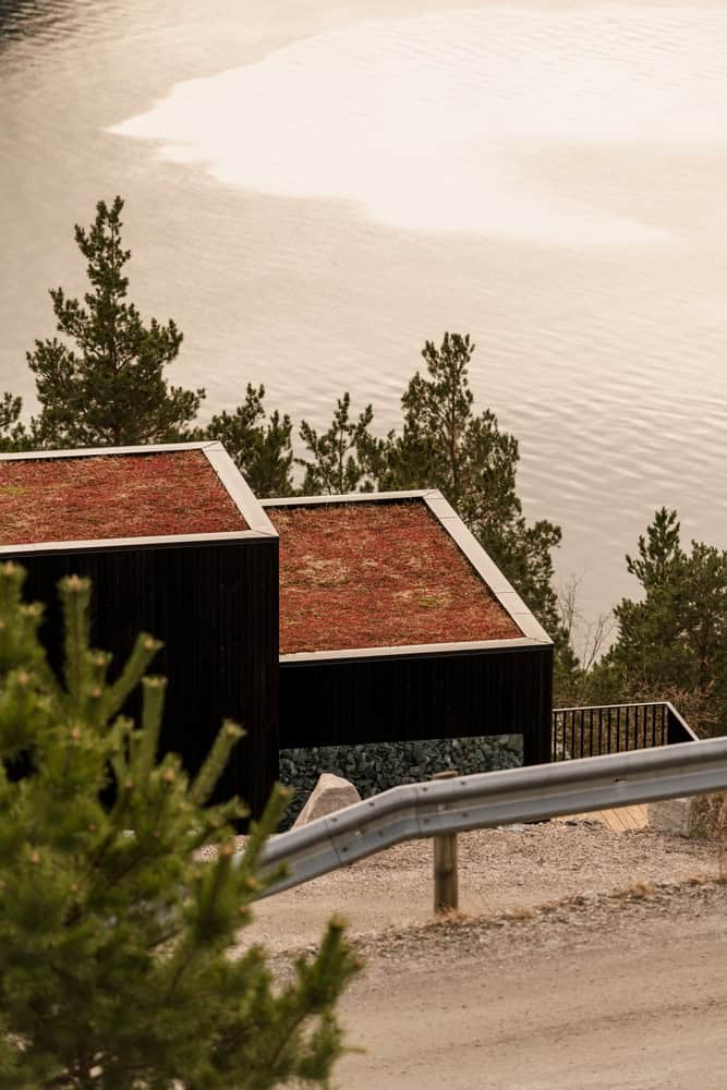 18-07 Holiday Home Rooftop from Road by OFFICE INAINN 18-07 Holiday Home by OFFICE INAINN, view from mountain road showing green roof and fjord backdrop