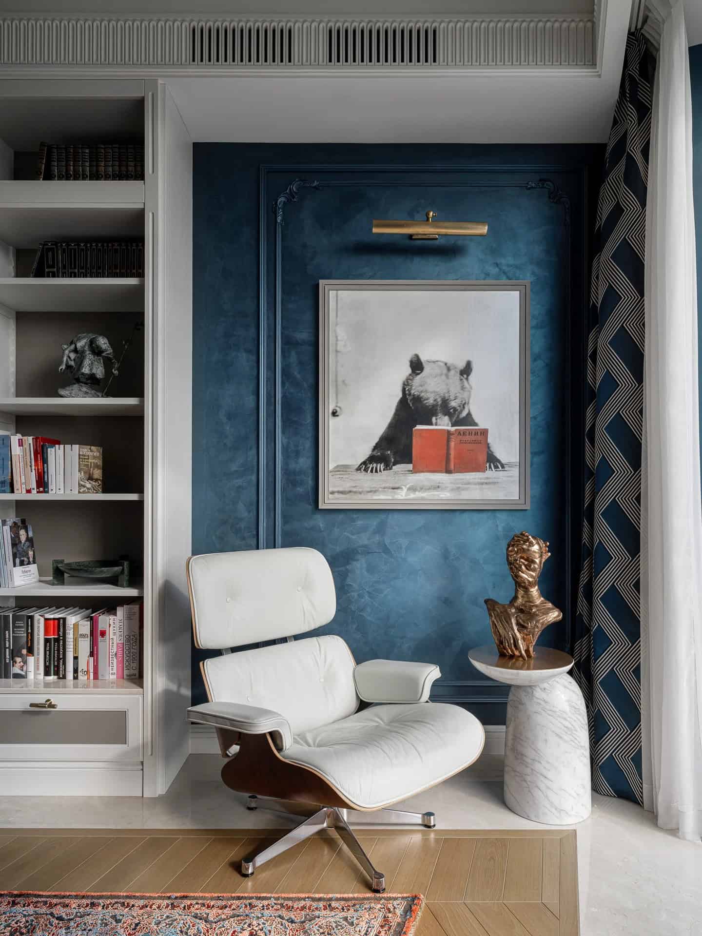 Apartment with a Parisian Mood for Collectors Blue Wall Art Corner by AABA Architects Blue accent wall with art and white Eames lounge chair — AABA Architects, Moscow