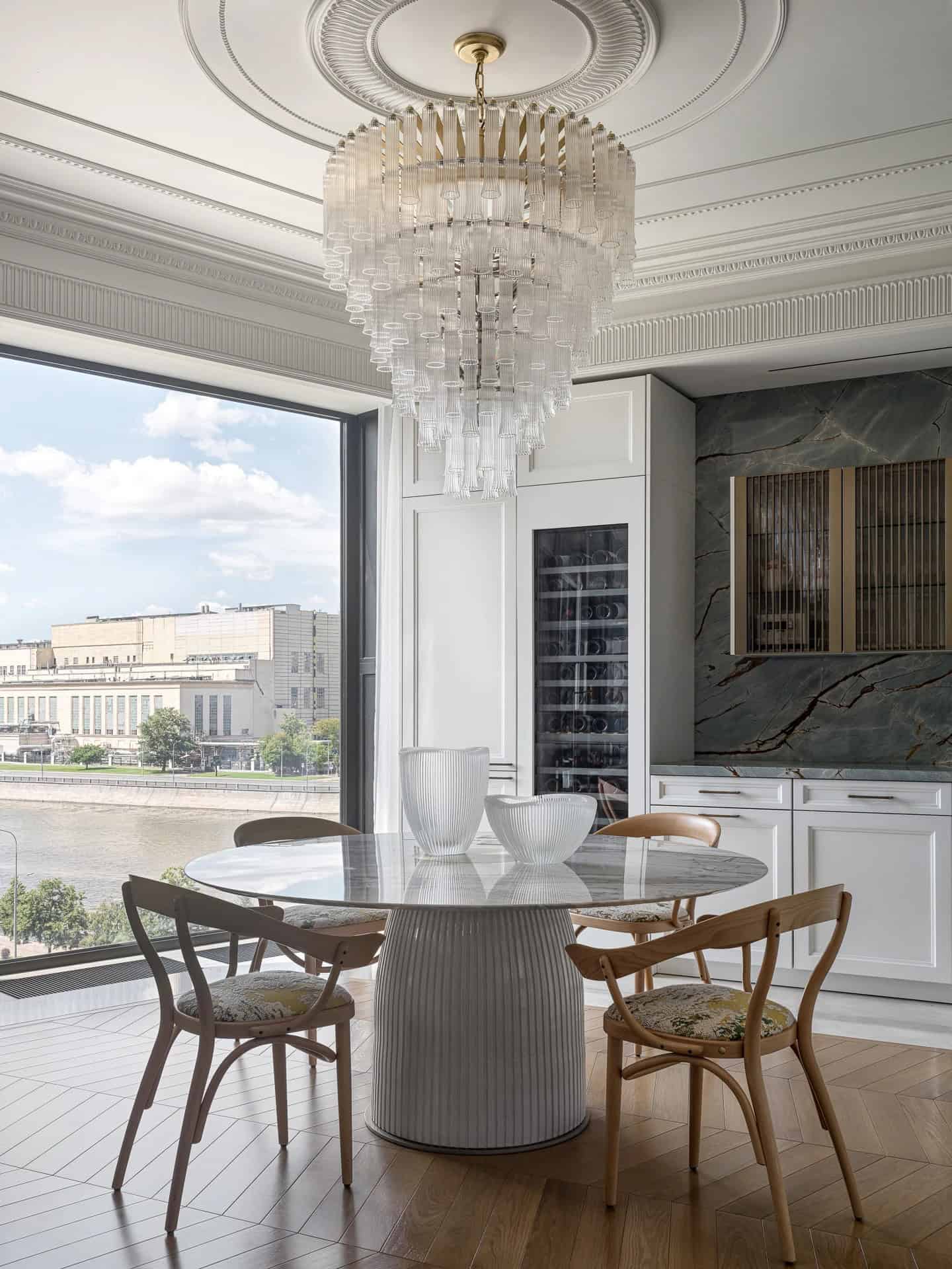 Apartment with a Parisian Mood for Collectors Dining Area Chandelier View by AABA Architects Dining area with round marble table and chandelier overlooking the river — AABA Architects, Moscow