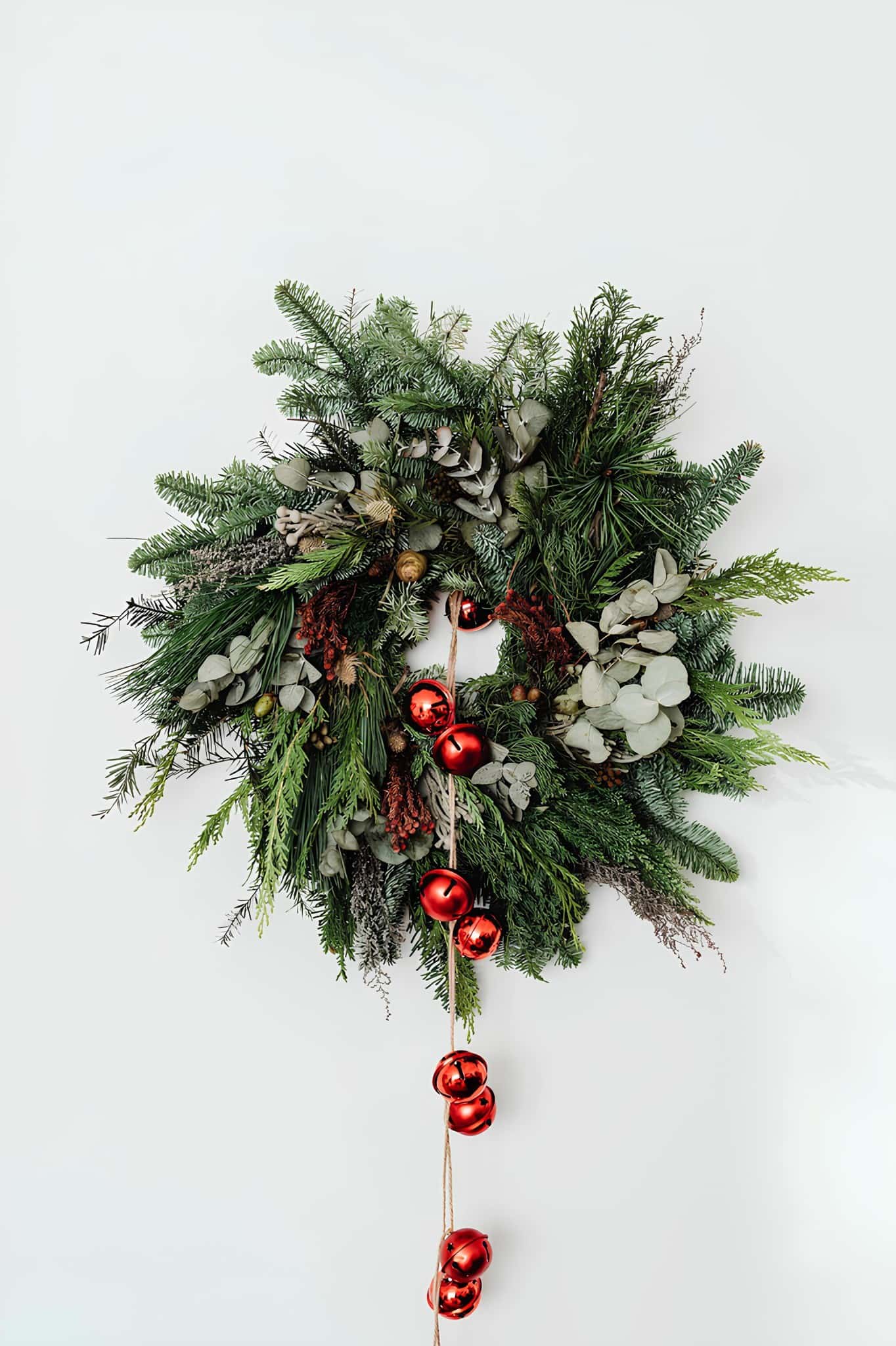Lush Christmas wreath decorated with pine, eucalyptus, and red ornaments for holiday decor.