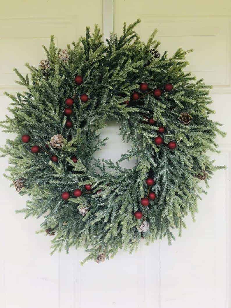 Frosted pine Christmas wreath with matte red berries and snowy evergreens