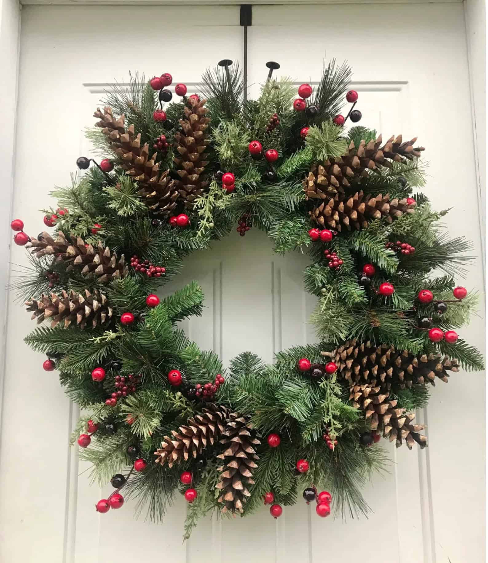 Oversized pinecones and red berries on lush evergreen Christmas wreath