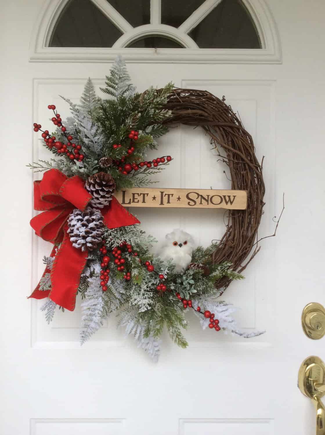 Grapevine wreath with red berries, pinecones, white owl and Let It Snow sign