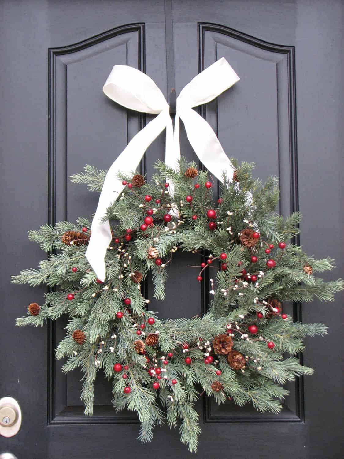 Traditional pine wreath with white bow, pinecones and red berries