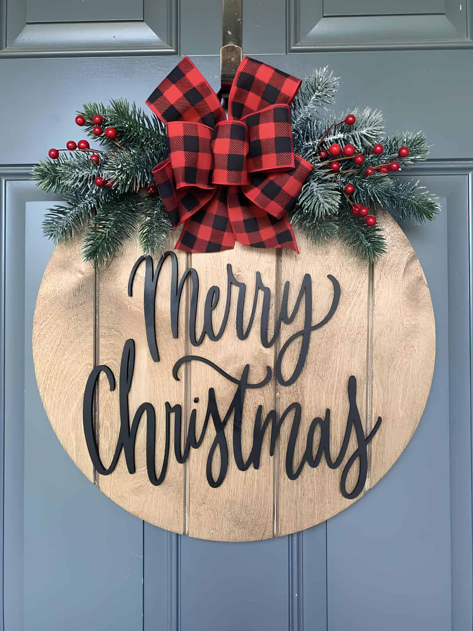 Wood round Merry Christmas door hanger with buffalo plaid bow, pine and red berries