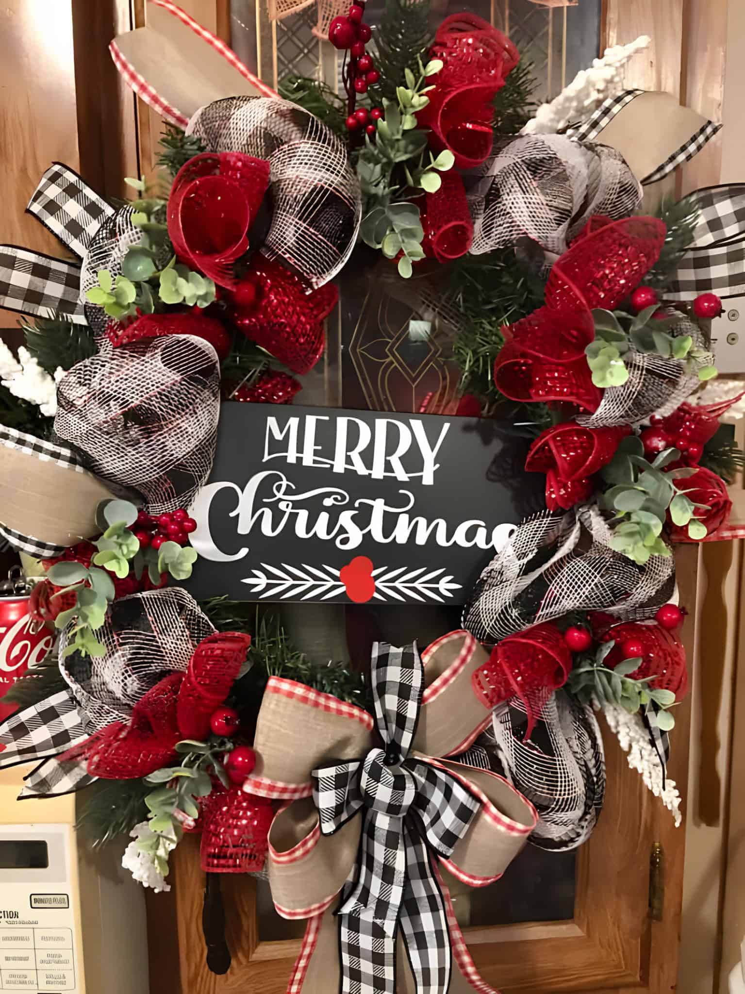 Vibrant Christmas wreath with red and black checkered, burlap, and mesh ribbons, adorned with holiday greenery, berries, and a "Merry Christmas" sign, perfect for festive home decor.