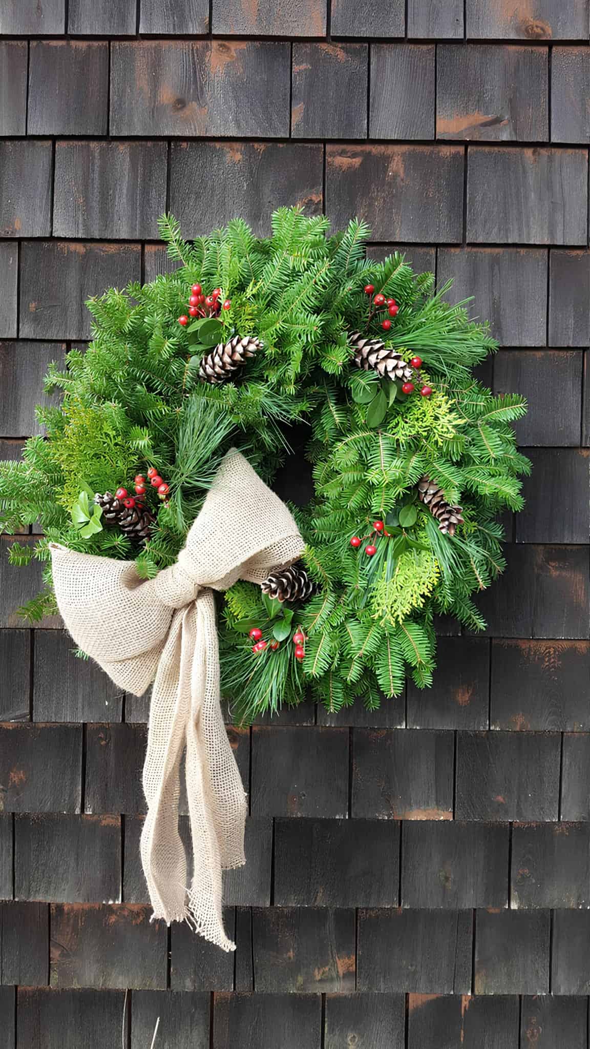 Evergreen Christmas wreath with burlap bow, pinecones, and red berries