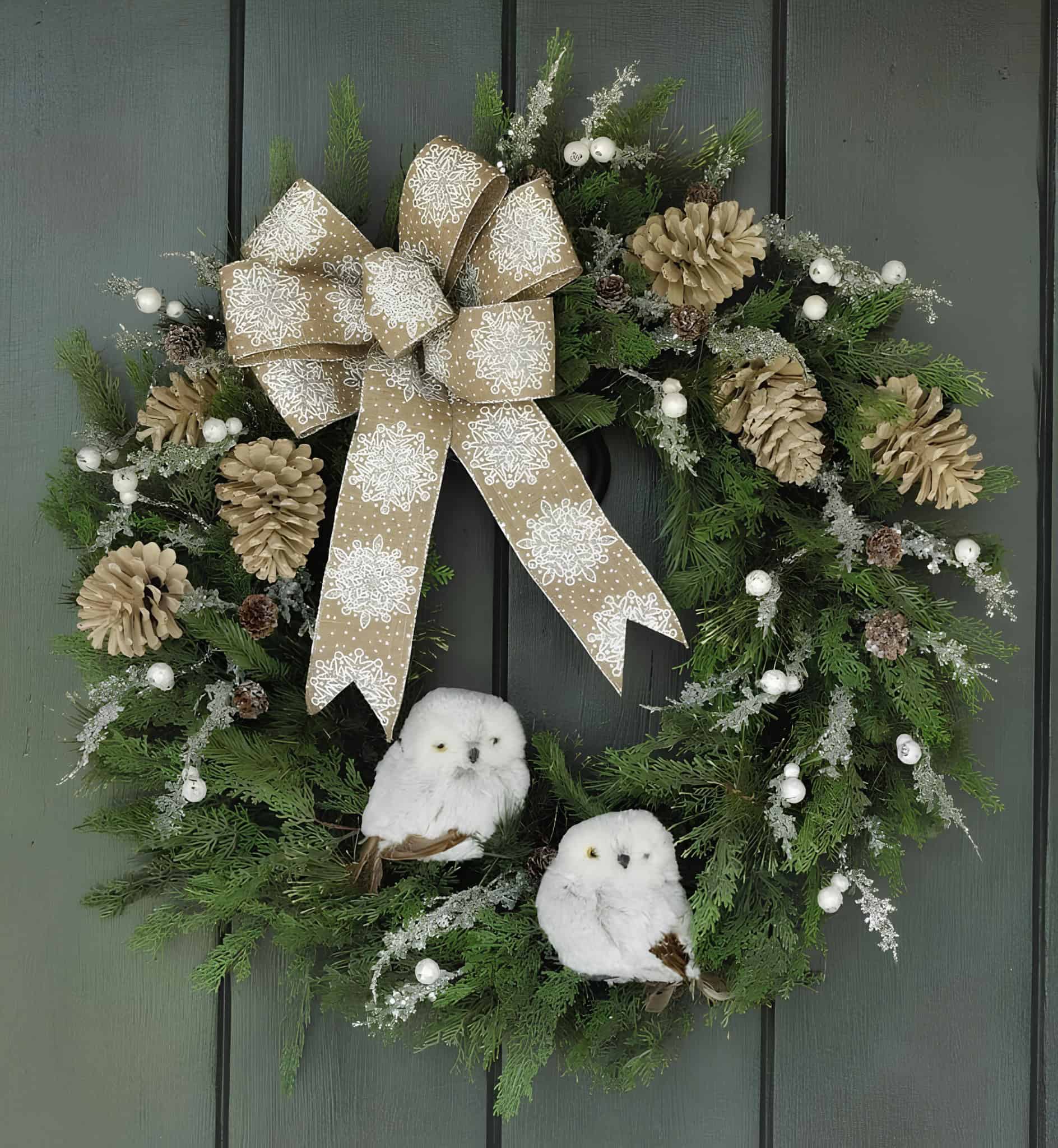 Green Christmas wreath with pinecones, snowy owls and burlap bow