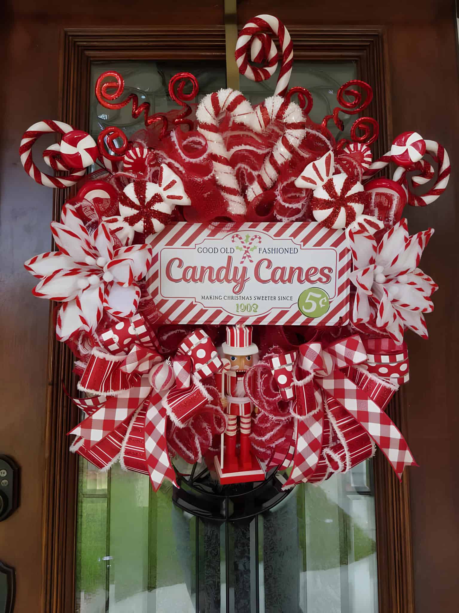 Red and white candy cane wreath with ribbons, peppermint swirls and nutcracker