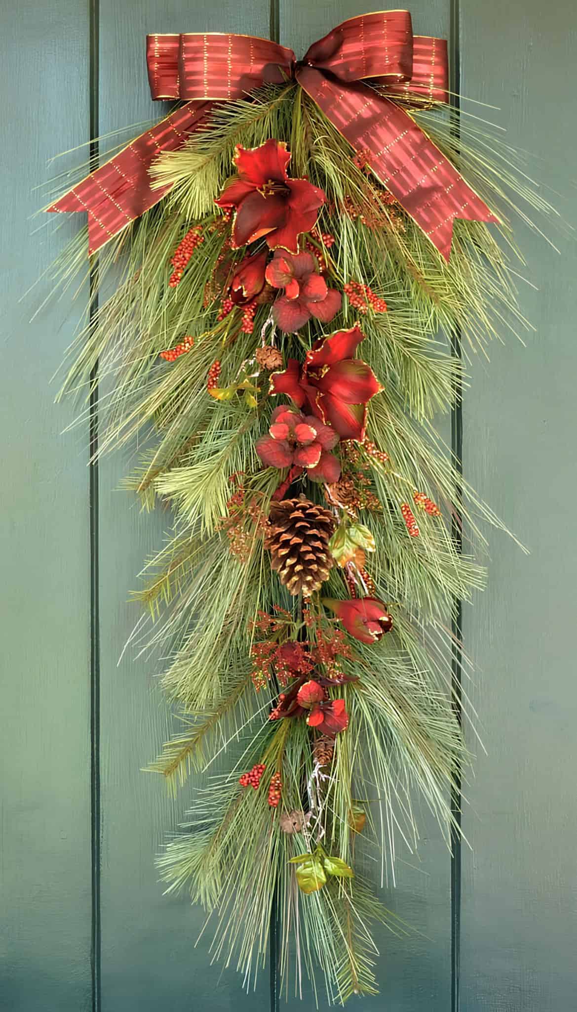 Vertical swag wreath with pine, red amaryllis, berries and a red bow