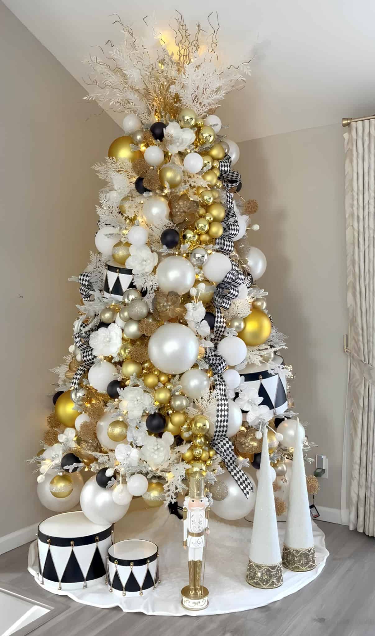 Black, white and gold Christmas tree with harlequin drums, ribbons, and nutcracker figurine