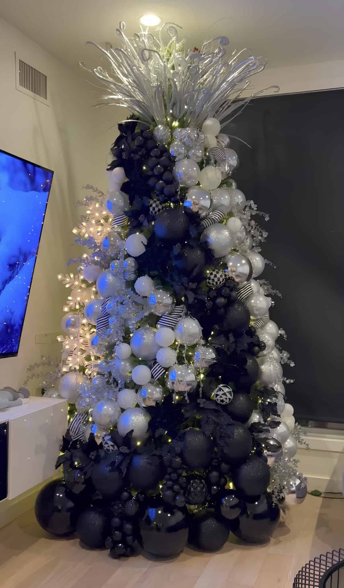 Black, white, and silver Christmas tree with modern ornaments and metallic branches