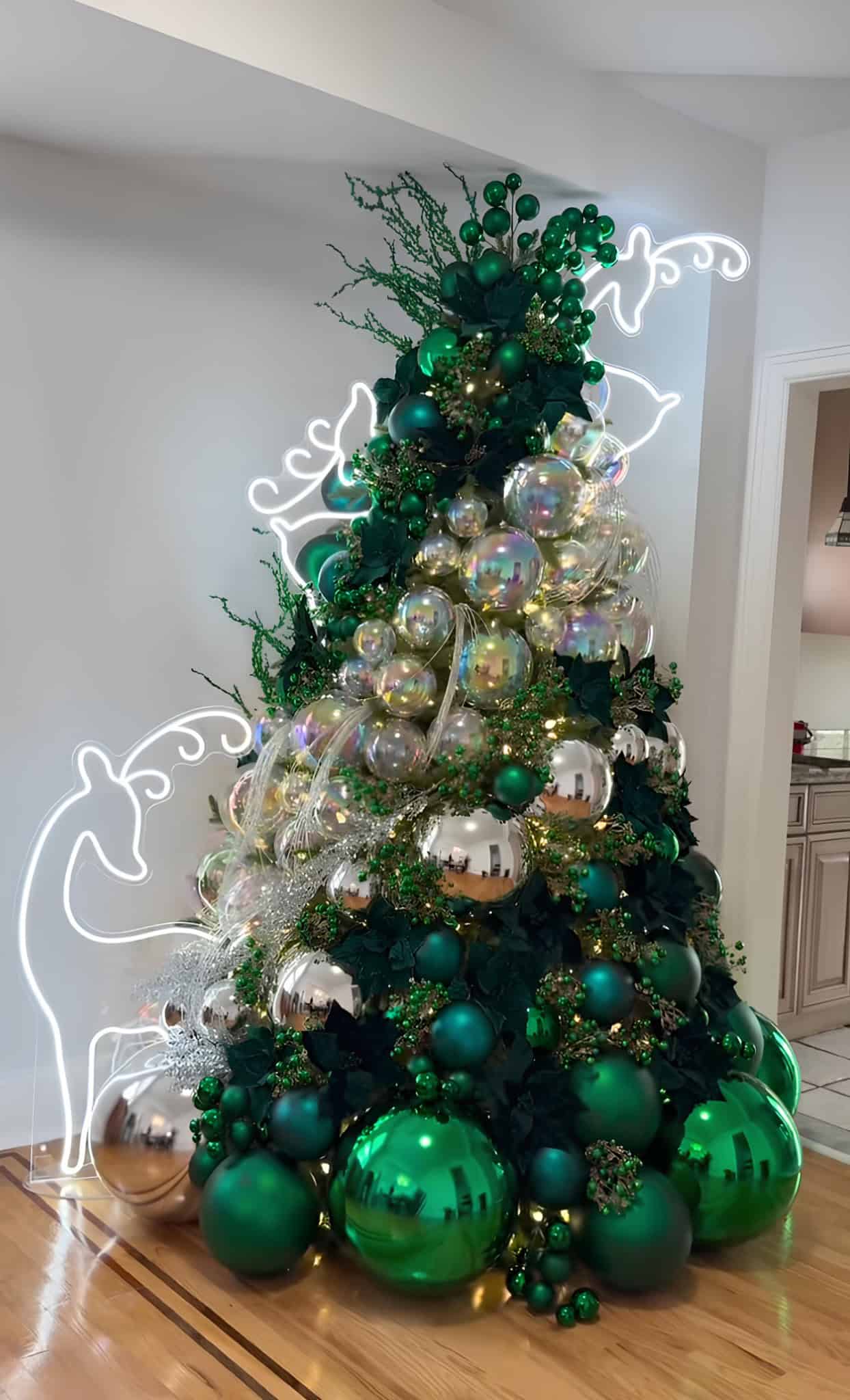 Emerald green and silver Christmas tree with iridescent baubles and neon reindeer lights