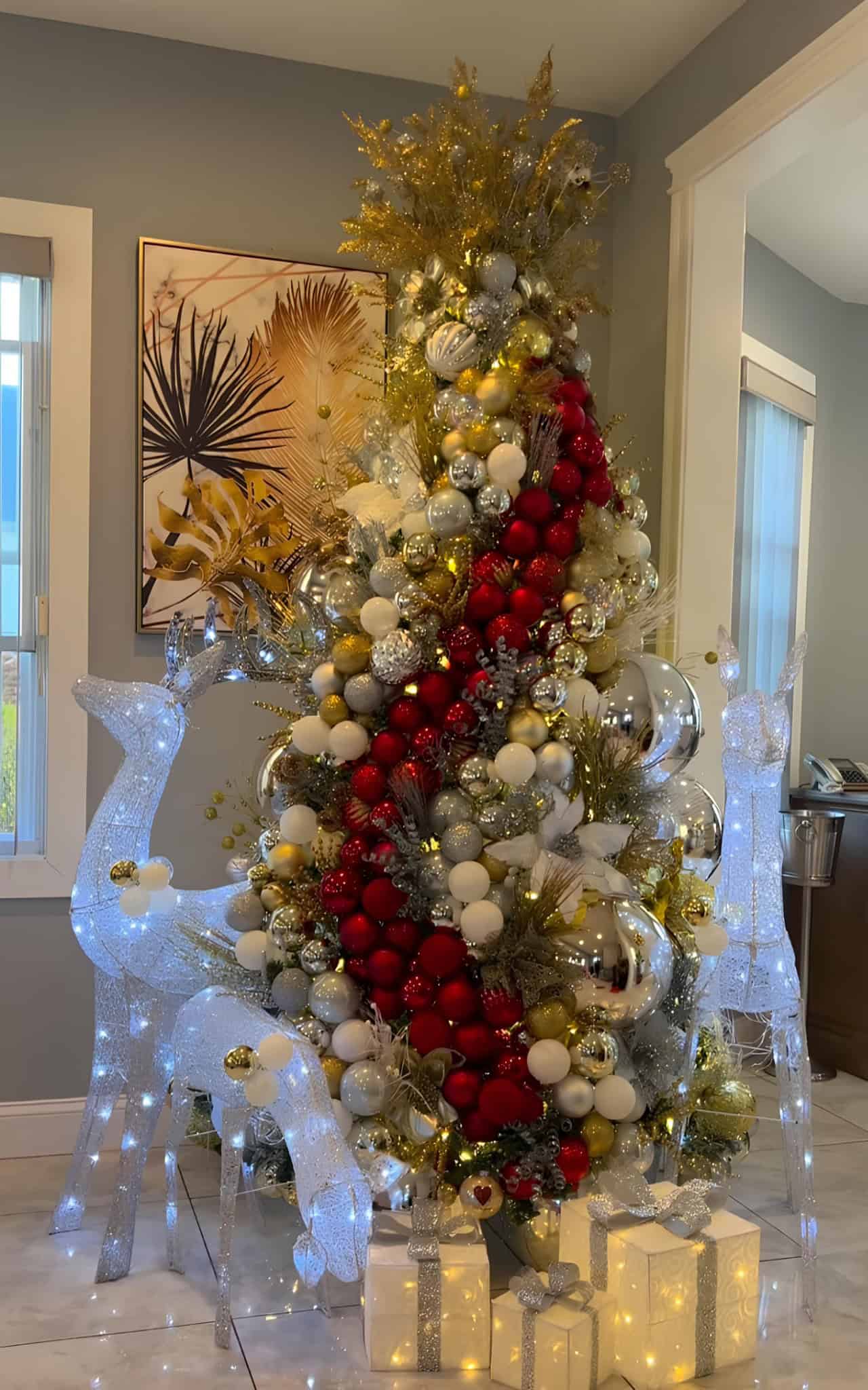 Gold, silver, and white tree with a bold red ribbon cascade and light-up deer