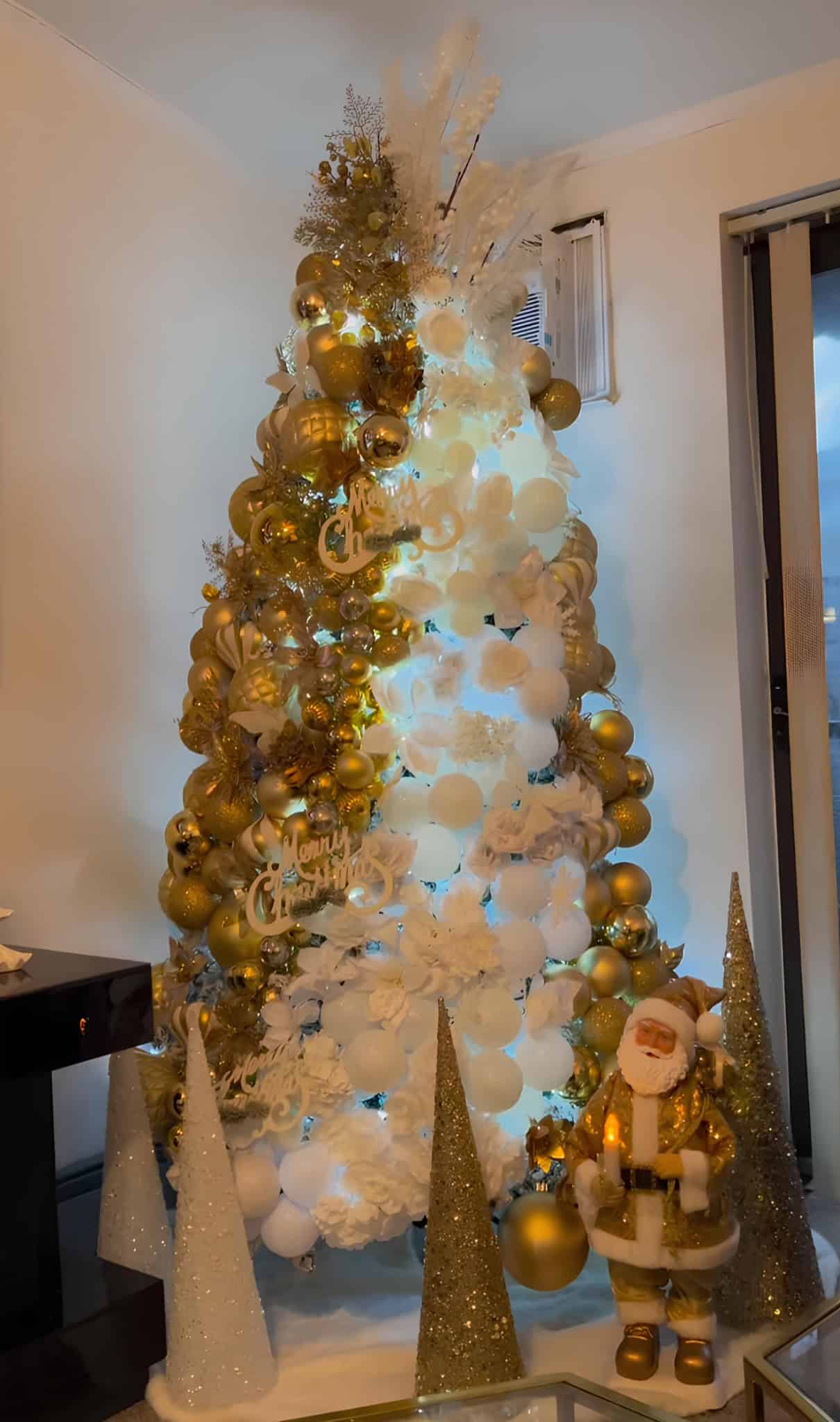 Gold and white Christmas tree with glowing ornaments and modern Santa accent
