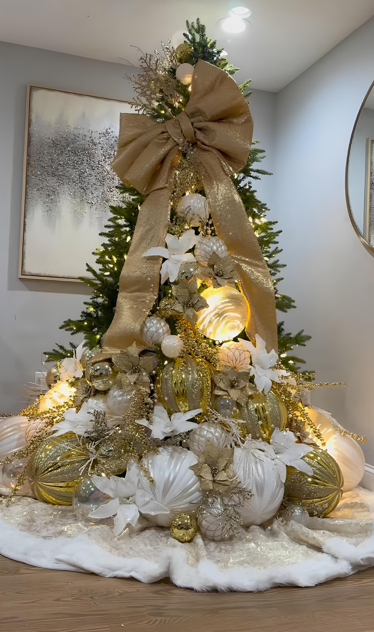 Gold and white Christmas tree with oversized bow, poinsettias, and glowing ornaments