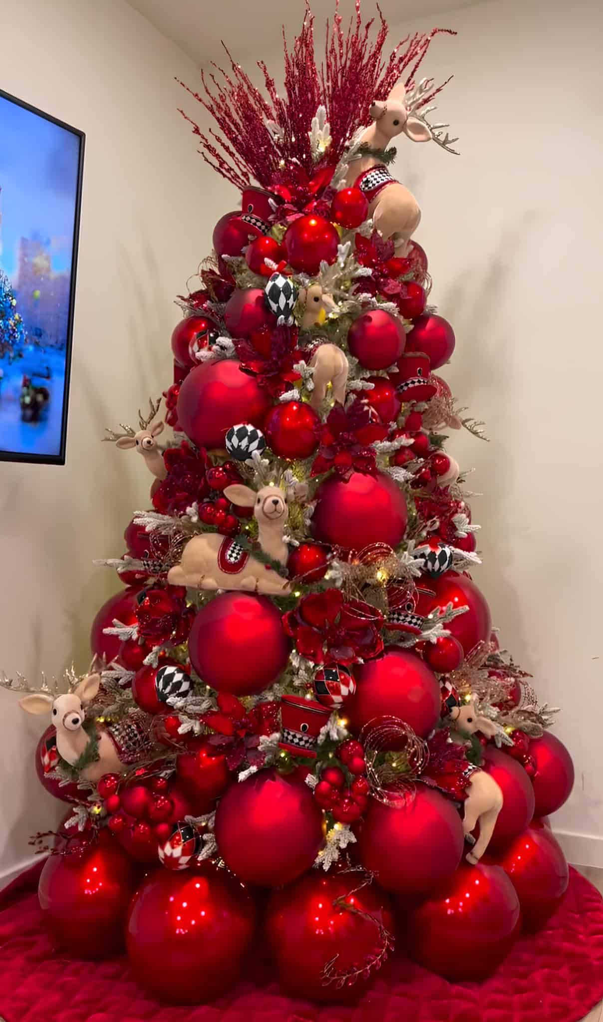 Vibrant red Christmas tree with plush reindeer ornaments and whimsical accents
