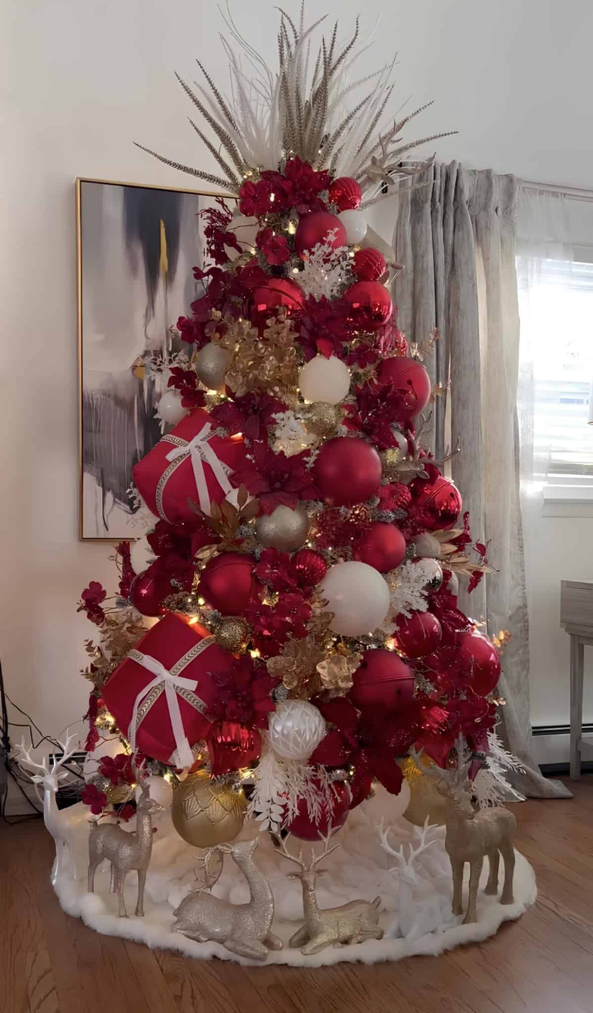 Modern red and gold Christmas tree with gift boxes and reindeer ornaments