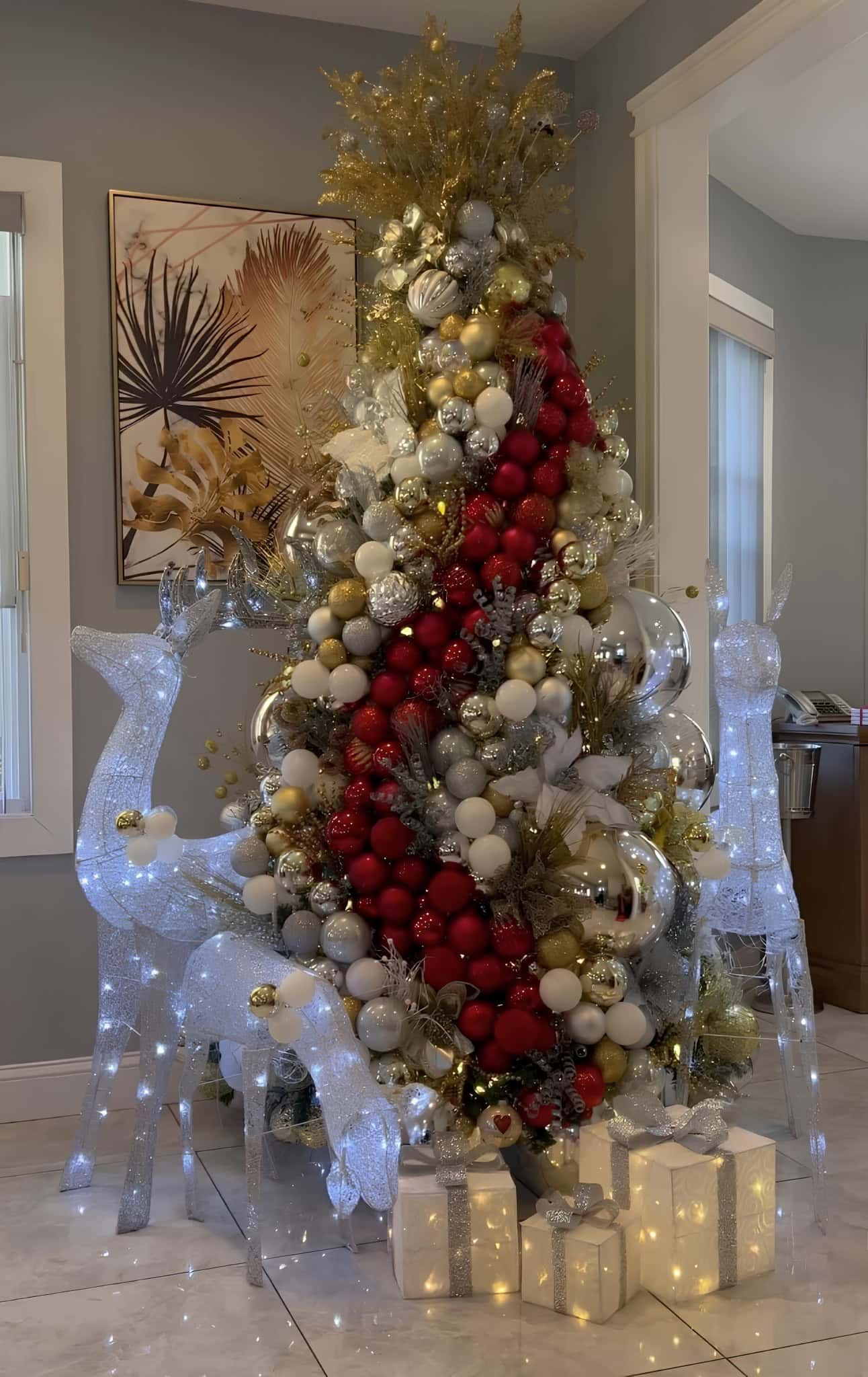 Red, gold, and silver Christmas tree with cascading ribbon and light-up deer figures