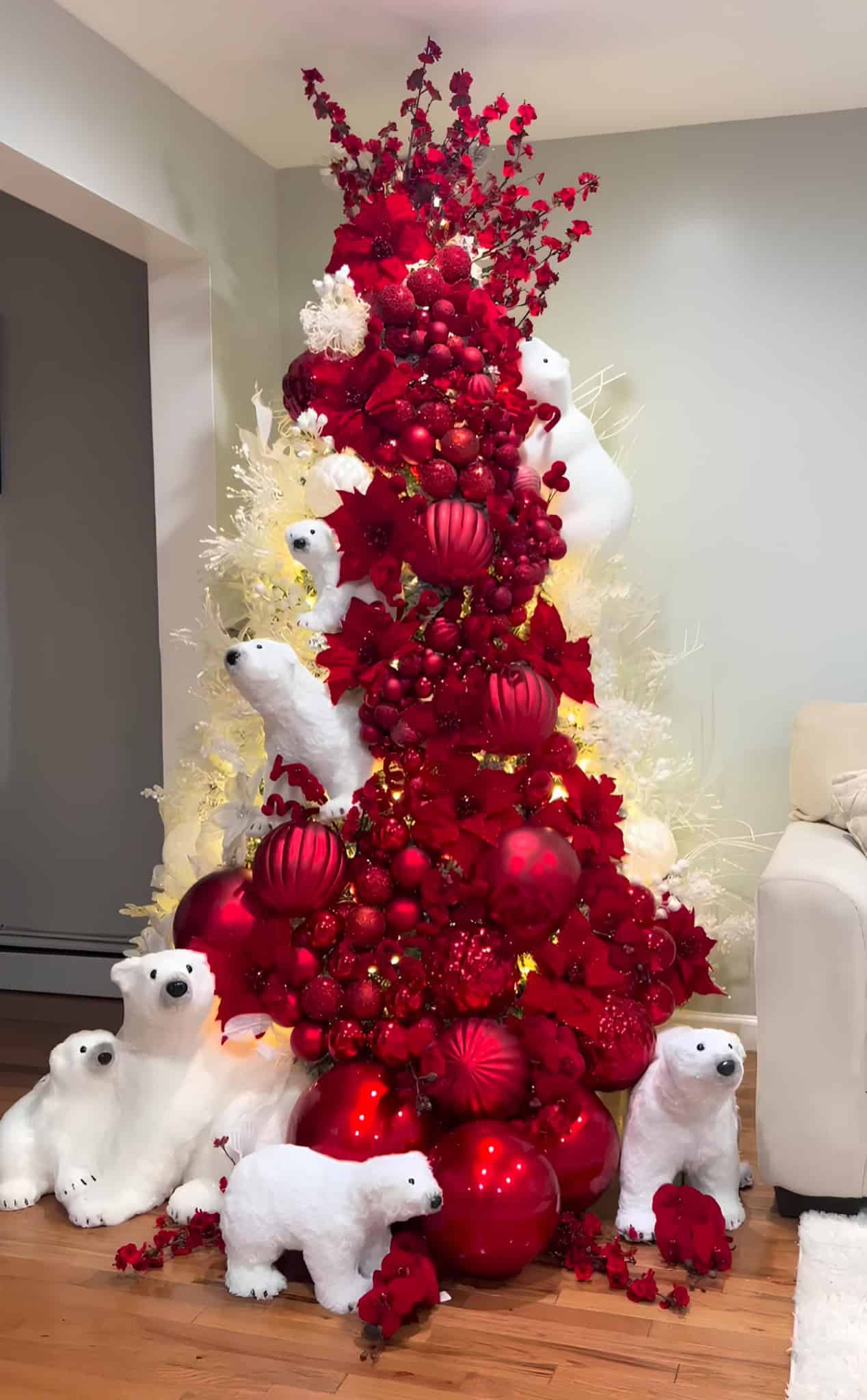 Bold red Christmas tree with cascading ornaments, poinsettias, and white polar bear figures