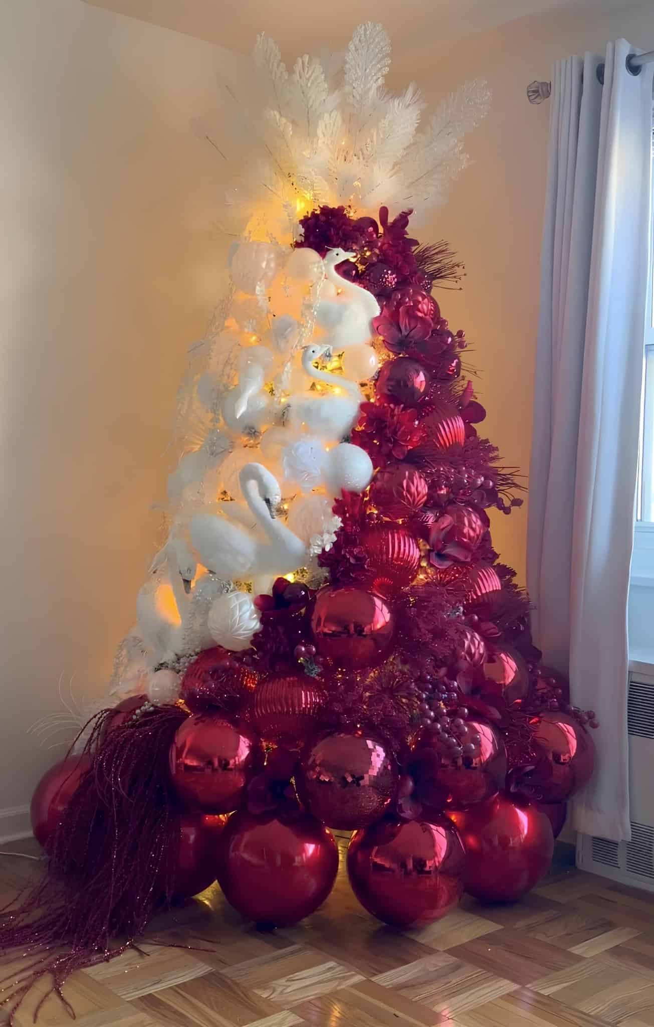 Half red half white Christmas tree with swan ornaments and oversized baubles