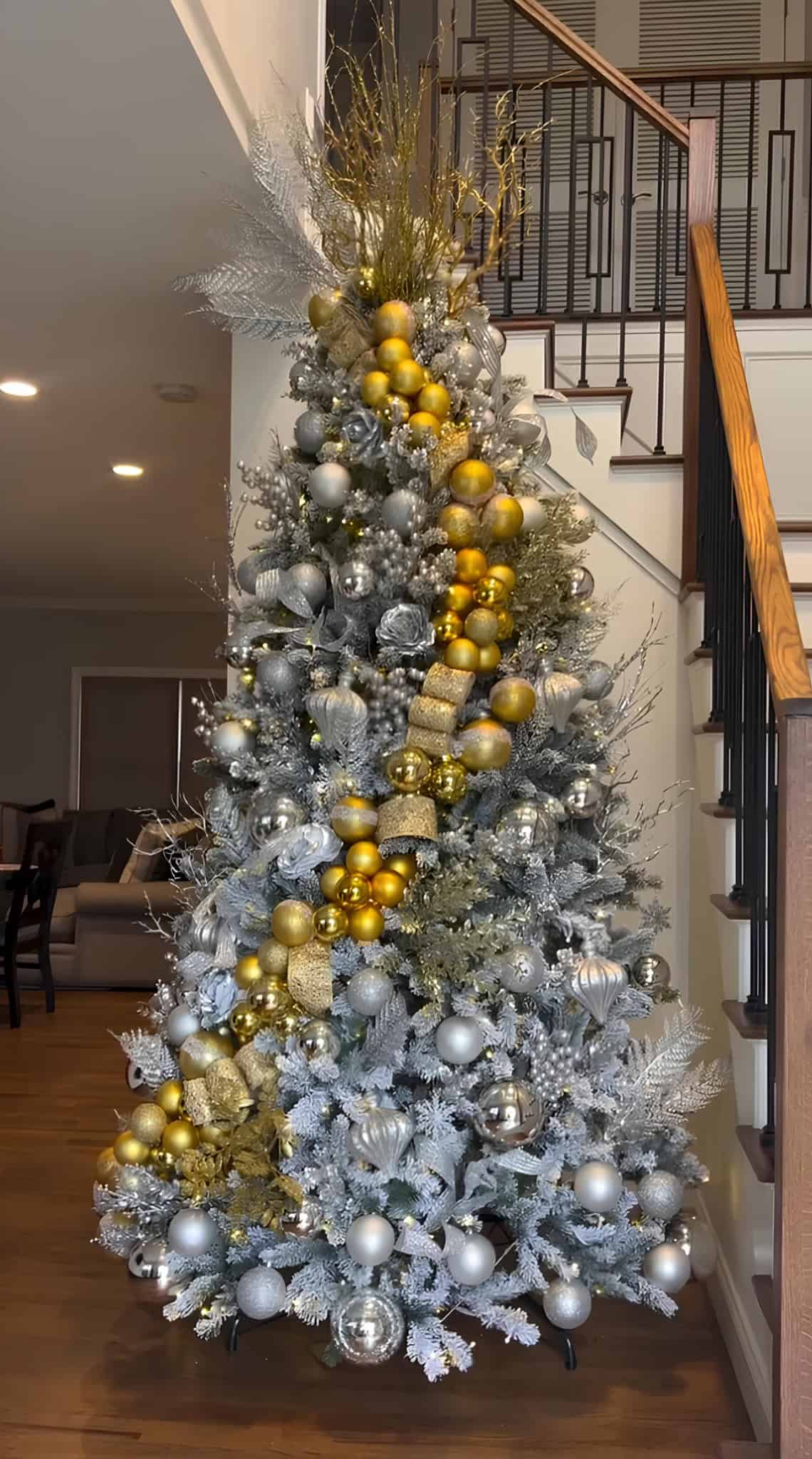 Silver and gold Christmas tree by staircase with frosted ornaments and glitter ribbon