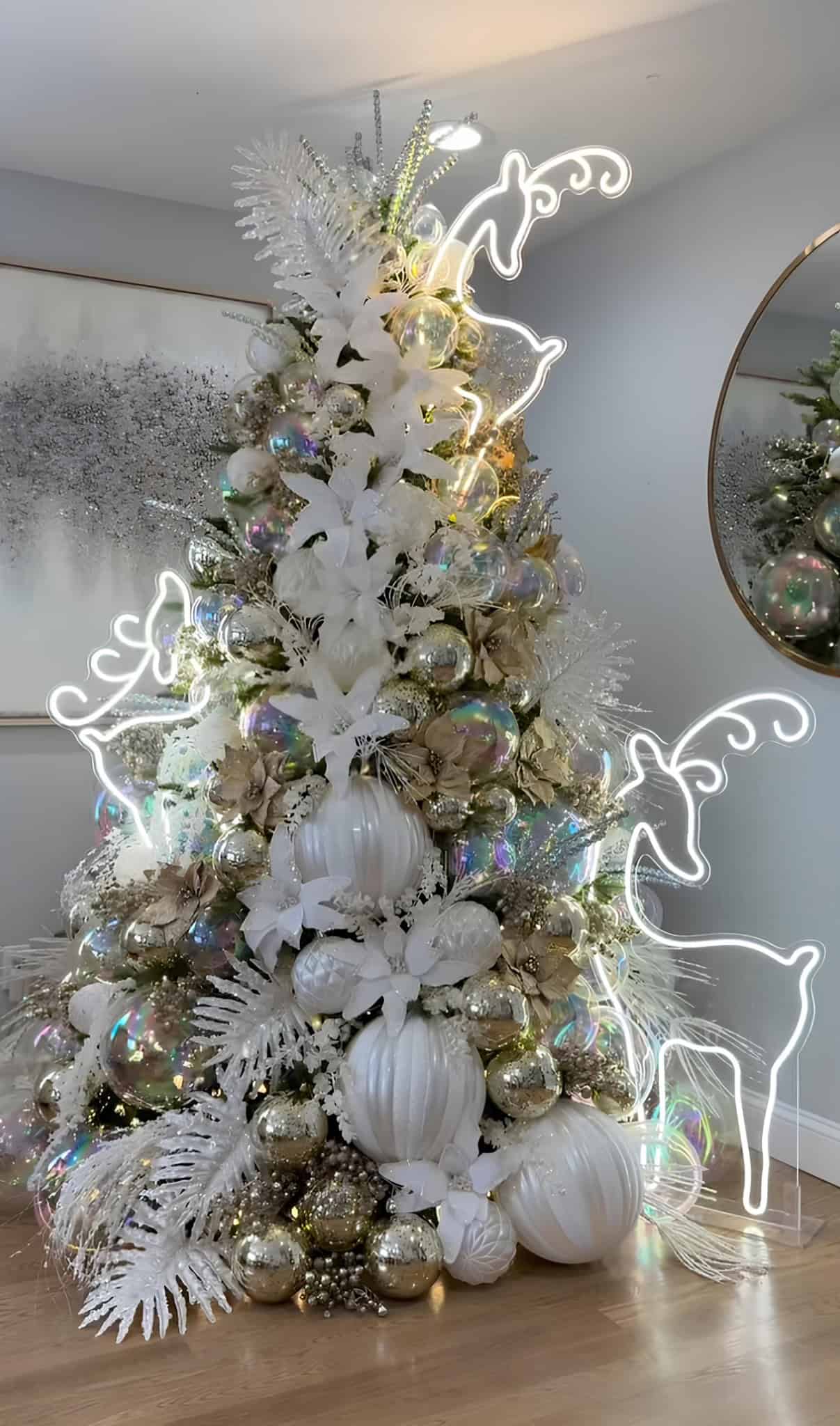 White and gold Christmas tree with oversized baubles, iridescent ornaments, and neon reindeer