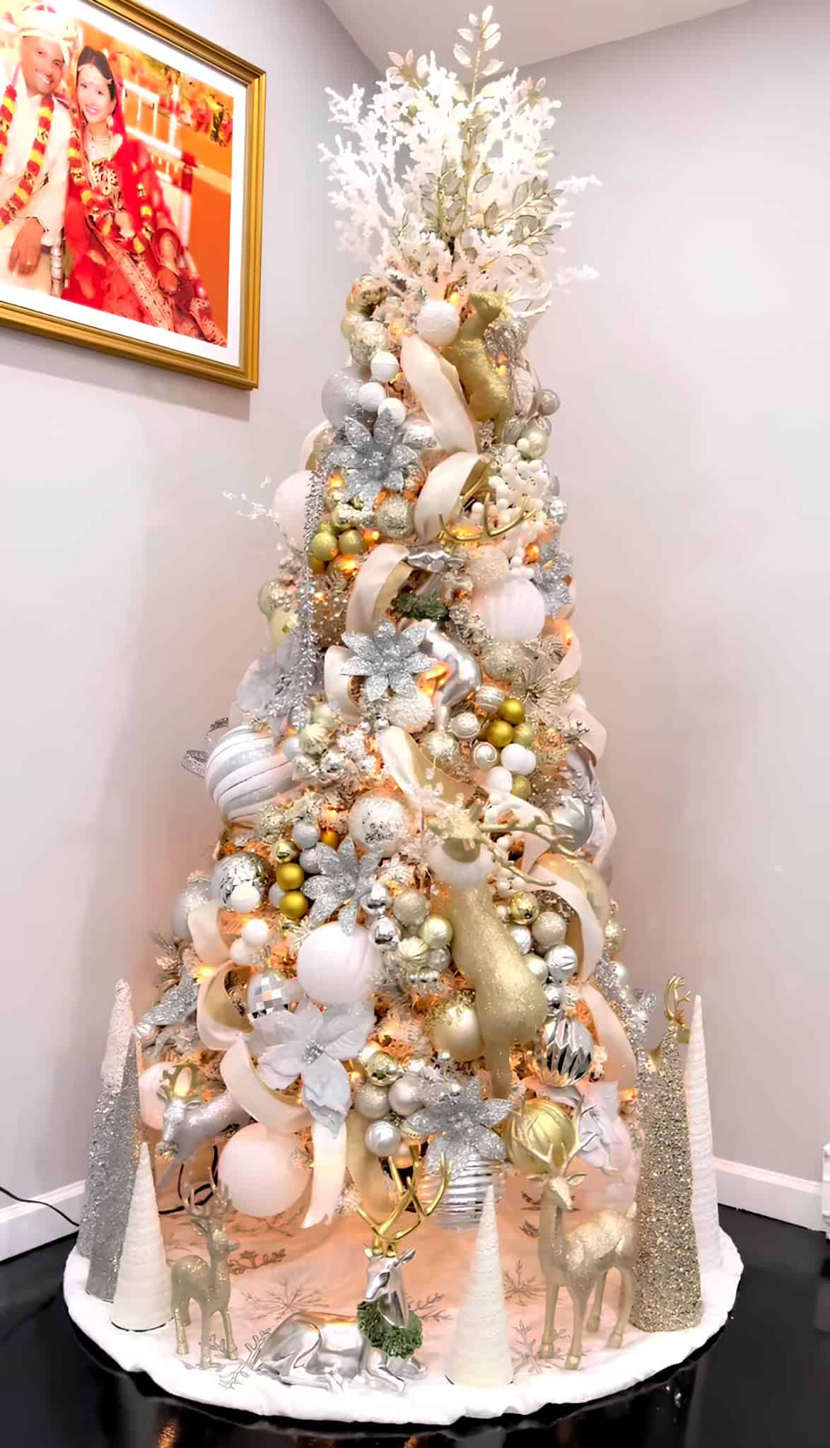 Elegant white and gold Christmas tree with silver accents and reindeer figurines