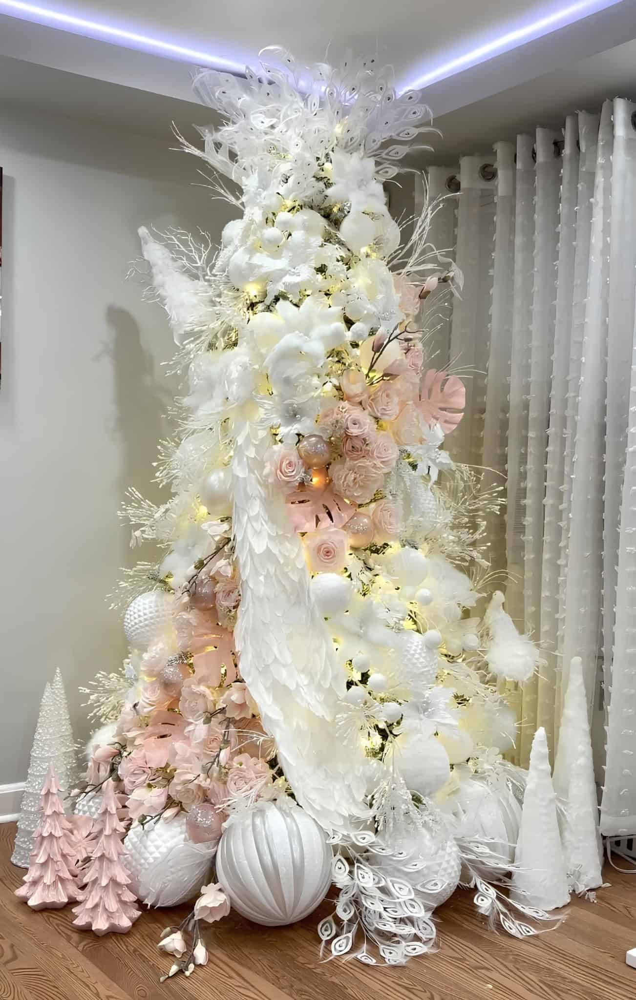 White and peach Christmas tree with peacock feathers and floral ornaments