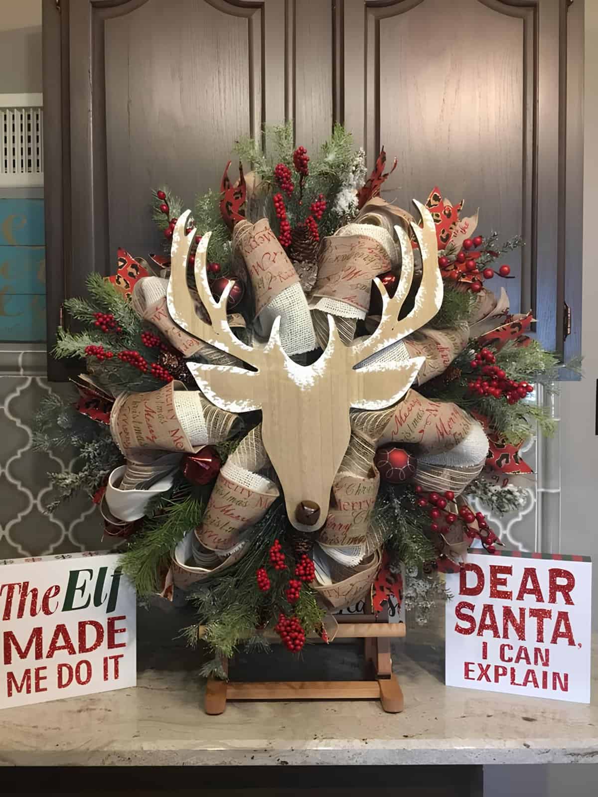Large deco mesh Christmas wreath with greenery, berries, and a wood deer head centerpiece
