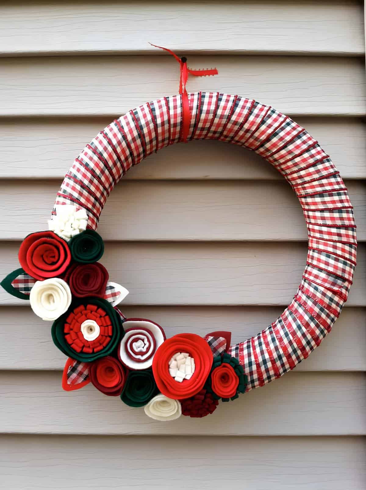 DIY Christmas wreath wrapped in plaid fabric with red, green, and white fabric flowers