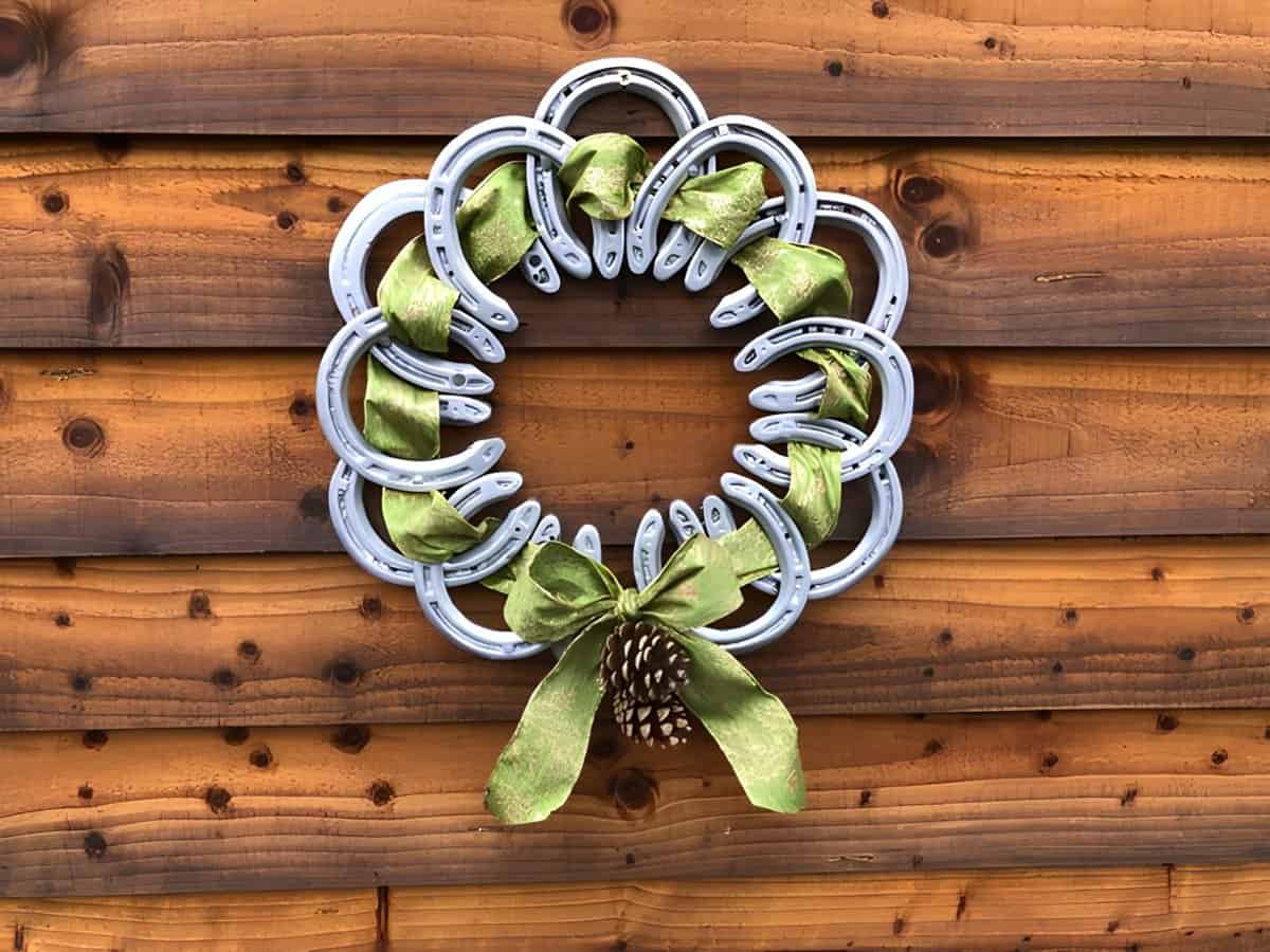 Horseshoe wreath with green ribbon, bow, and pinecone accent