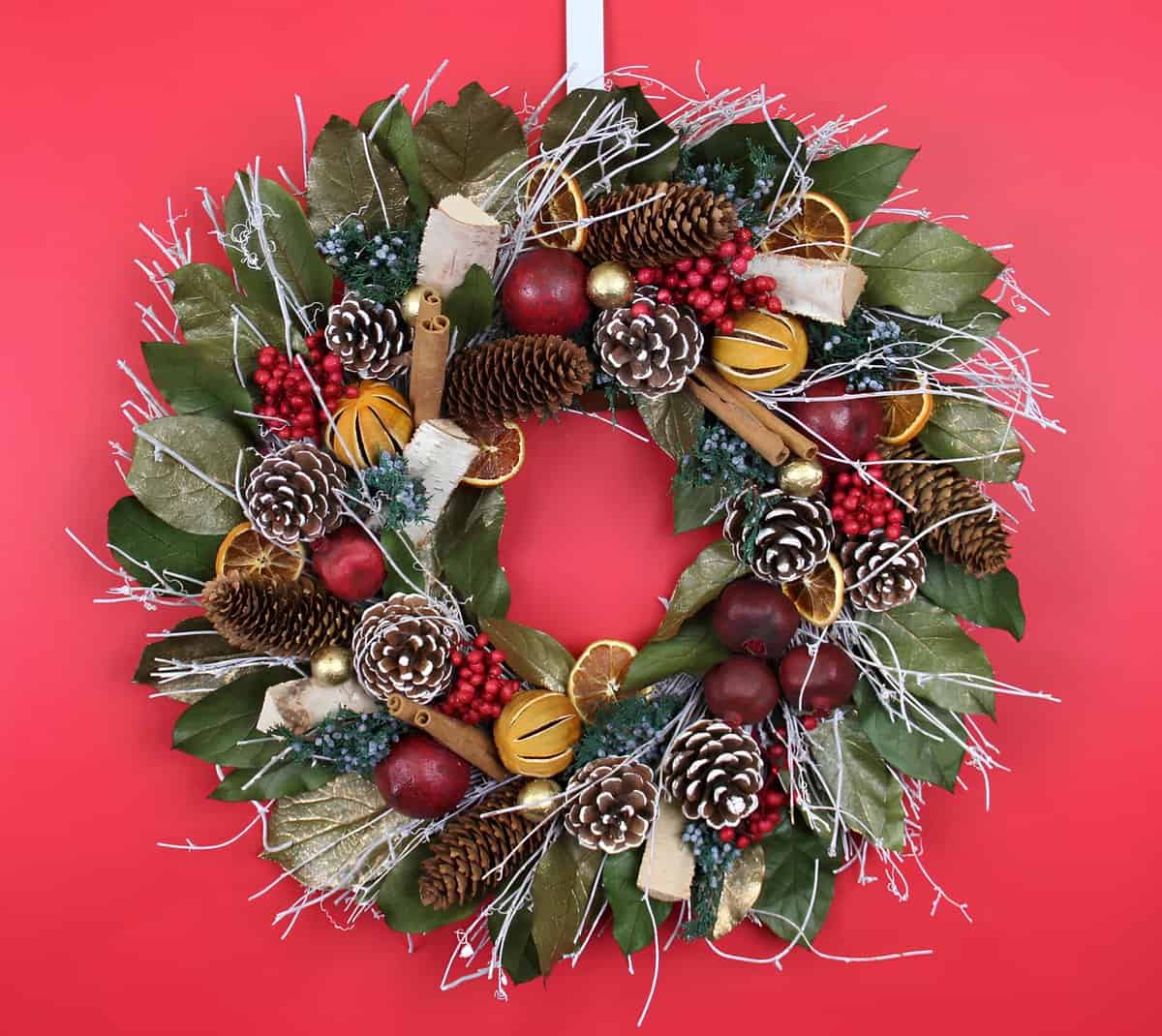 Magnolia leaf wreath with pinecones, red berries, cinnamon sticks, and dried orange