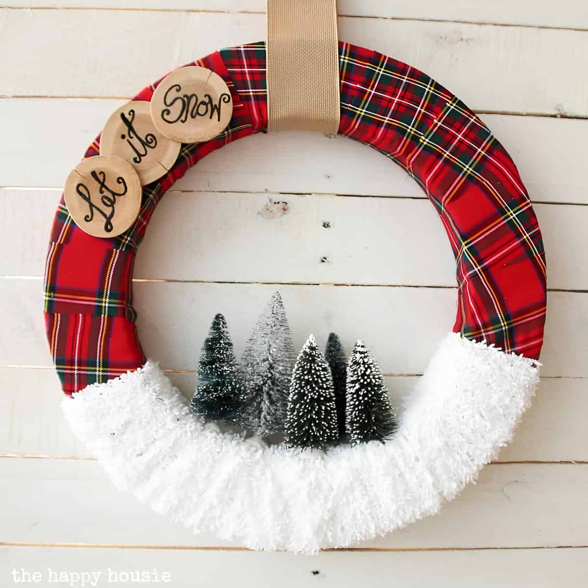 Plaid-wrapped Christmas wreath with faux snow and bottle-brush trees