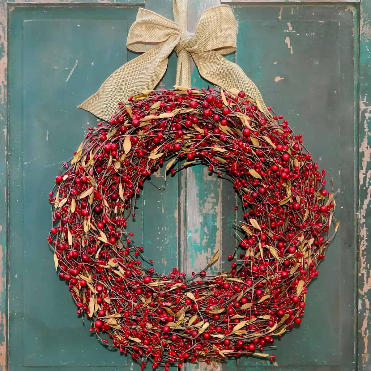 Rustic Christmas wreath made of red berries and leaves tied with a burlap bow
