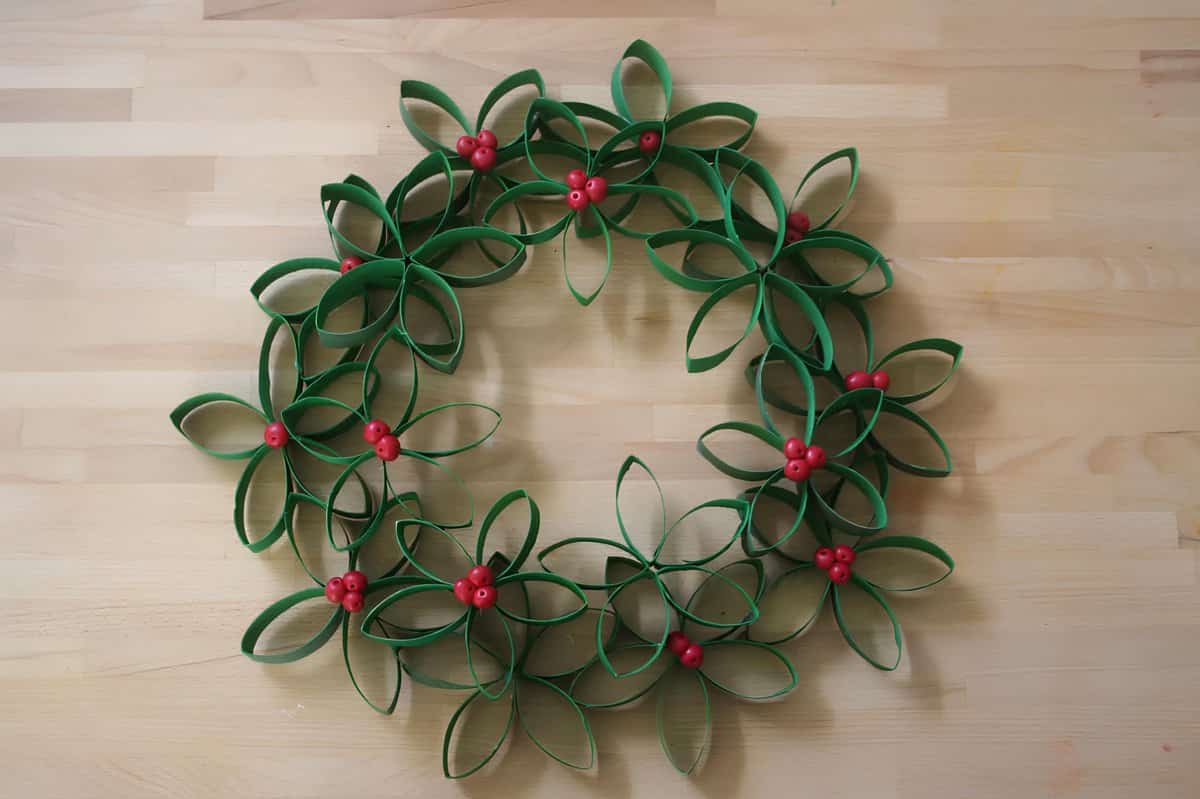 Handmade Christmas wreath crafted from painted paper rolls shaped into flowers with red berries